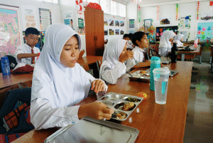 Ilustrasi - para siswa SD menikmati makanan dari Program MBG.