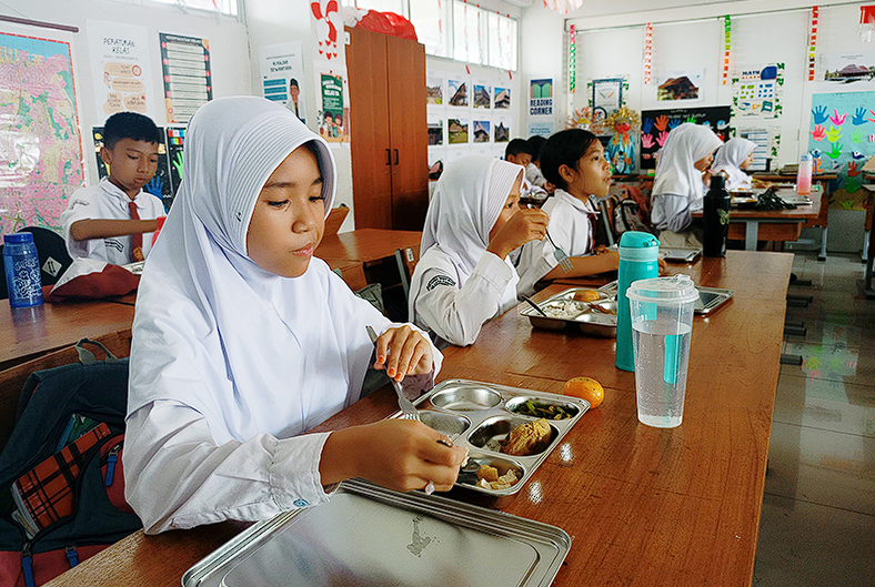 Ilustrasi - para siswa SD menikmati makanan dari Program MBG.